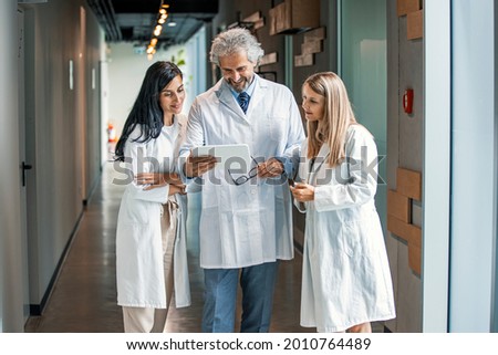 Shot of a group of medical practitioners having a discussion in a hospital. Team of doctors having discussion in hospital corridor. Group of medical staff discussing in clinic hallway.