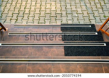 Closeup of ceramic tiles covering porch stairs with rubber anti slippery stripes on it. Royalty-Free Stock Photo #2010774194