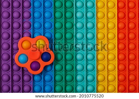Trendy toy spinner Simple Dimple on multi-colored surface POP IT. Tap on bubble, finger game.  Royalty-Free Stock Photo #2010775520
