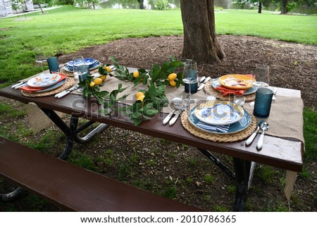 A picnic table with plates and other dishes on it. There are candles and a lemon garland on the table. Picture taken in O’Fallon, Missouri at the Fort Zumwalt Park.
