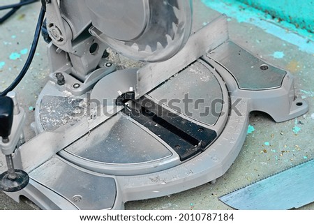 An angular circular saw stands with a saw and a tape measure on the concrete floor. Construction and construction materials.Use a dangerous tool in work. close up