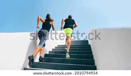 Stairs runners running up staircase training hiit workout. Couple working out legs and cardio at fitness gym. Healthy active lifestyle sport people exercising climbing staircase in urban city. Royalty-Free Stock Photo #2010794954