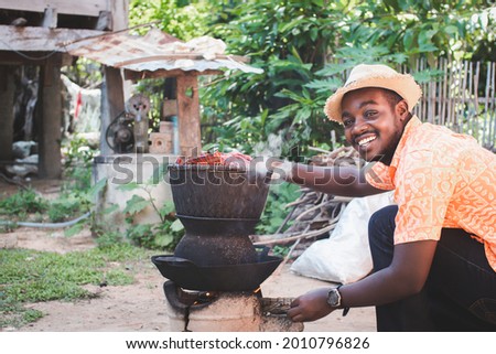 African man happily to cooking with a charcoal stove