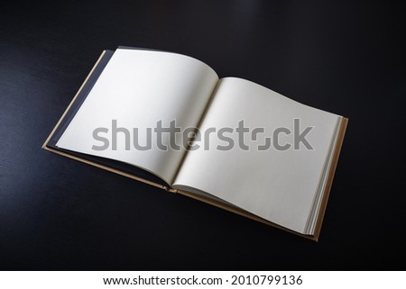 Blank open book on black paper background.