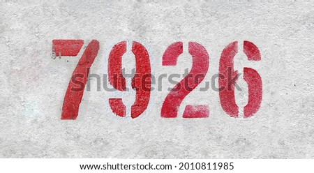 Red Number 7926 on the white wall. Spray paint. Number seven thousand nine hundred and twenty six.