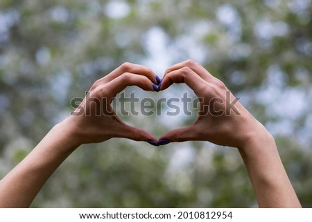 Womens hands in the shape of a heart, outdoor lifestyle. Abstract background with copy space for text