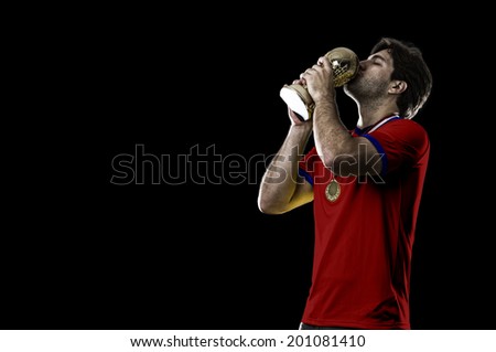 Chilean soccer player, celebrating the championship with a trophy in his hand. On a black background.