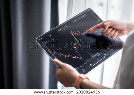 Hand holding digital tablet display stock market data with graph and chart for analyze and check before trading stocks online Royalty-Free Stock Photo #2010824936