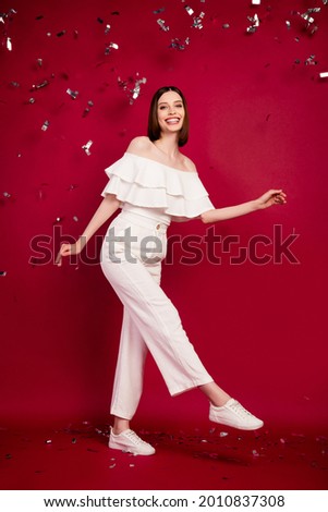 Vertical full size photo of nice brown hairdo millennial lady walking red carpet wear top pants isolated on red background