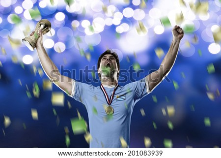 Uruguayan soccer player, celebrating the championship with a trophy in his hand. On a blue lights background.