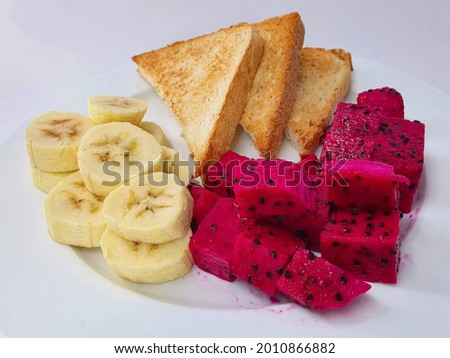 toast bread with banana and dragon fruit on white plate, isolated in white background.