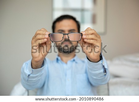 arab Man with a poor eyesight trying to adjust his glasses to see better