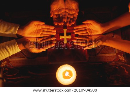 Praying hands with faith in religion and belief in God with lighting candle at night time.