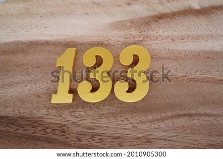 Gold numerals 133 on a dark brown to off-white wood pattern background.