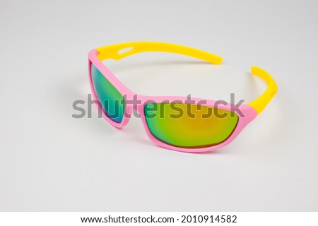 Children's glasses for cycling and sports. Made of pink plastic with yellow temples and UV-resistant lenses. Picture taken on a white background.
