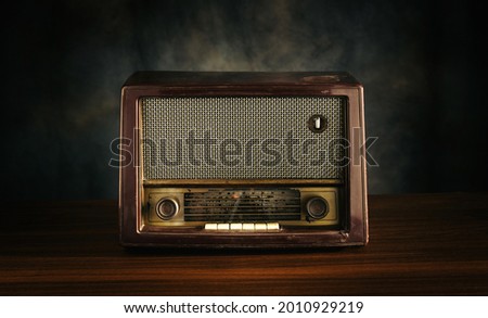 Front view, retro old fashioned radio receiver on wooden table on black background. Royalty-Free Stock Photo #2010929219