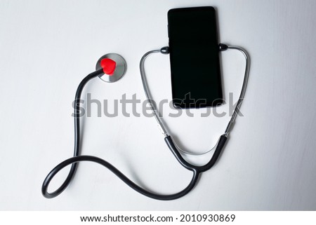 Smartphone being diagnosed with a stethoscope isolated on white background with copy space. Phone repair and service concept. High quality photo