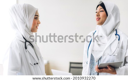 Two muslim asian woman doctor working with clipboard and tablet computer on desk in hospital.healthcare and medicine