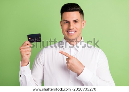 Photo of charming sweet young gentleman wear white shirt smiling holding bank card isolated green color background