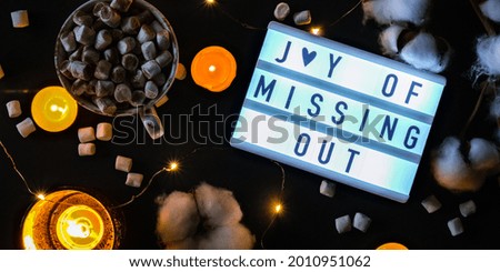 Lightbox with text JOMO Joy of Missing Out. The concept of relaxation from information and gadgets. Top view. Flat lay. Cup with cacao and marshmallows. Digital detox