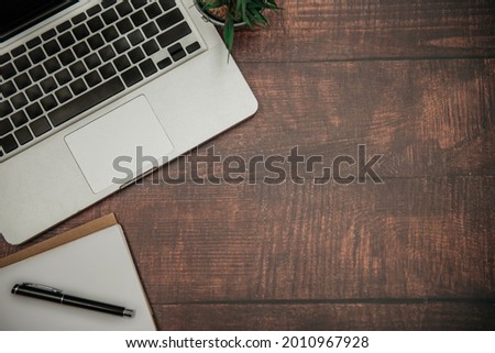 Office accessories laptop and notepad on a wooden table background. View from above.