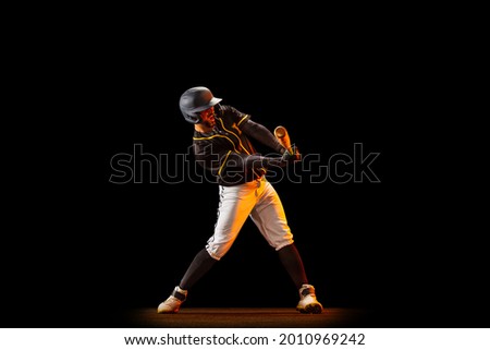 Professional baseball player, pitcher in sports uniform and equipment playing baseball isolated on black studio background in neon light. Competition, show and team sport concept. Copy space for ad.