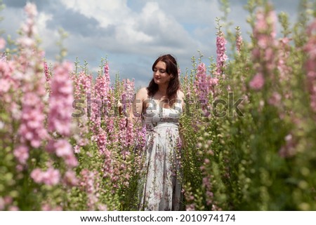 White woman in British Delphinium flower field walking and dancing through enjoying the floral scent of summer