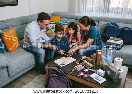 Mother explaining to her children how to use the radio while preparing emergency backpacks Royalty-Free Stock Photo #2010981218