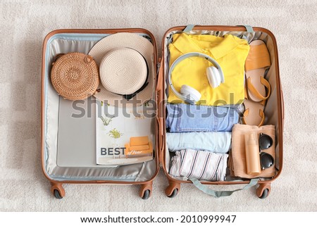 Packed suitcase with belongings on floor. Travel concept Royalty-Free Stock Photo #2010999947
