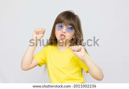 Photo of brunette hairdo impressed little girl dance wear blue sunglasse and yellow t shirt background