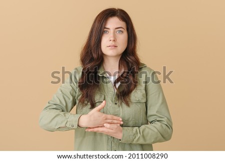 Young deaf mute woman using sign language on color background Royalty-Free Stock Photo #2011008290
