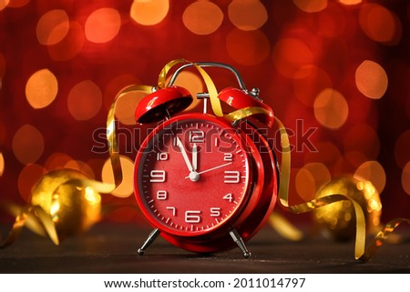 Alarm clock on table against blurred lights. Christmas time