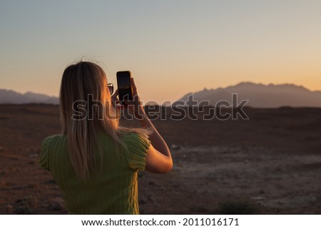 The girl takes a photo of the sunset and sunrise