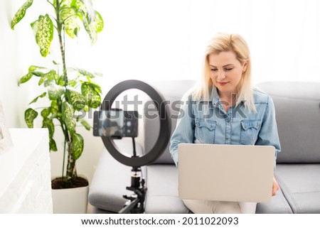 side view of young woman using smartphone at table with laptop