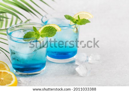 Two glasses of Blue Lagoon cocktail on light grey table with lemon and mint, space for text Royalty-Free Stock Photo #2011033388