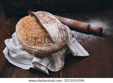 Crusty and decorative sourdough bread, handmade according to old italian recipes. Bread placed on a white table sheet on a wooden surface.