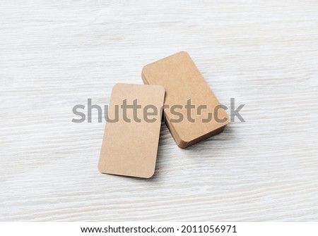 Photo of blank kraft business cards on light wooden background. Template for ID.