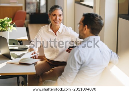 Business partners sitting at desk and discussing business strategy. Entrepreneurs doing discussion on new ventures in office. Royalty-Free Stock Photo #2011094090