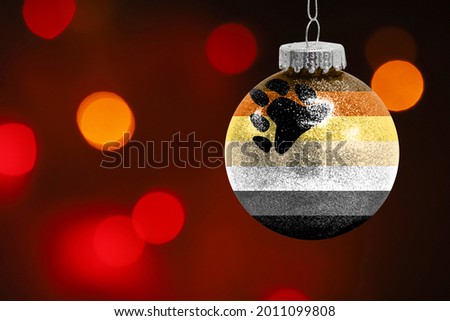 Colorful blurred background and applied the flag of Bear Brotherhood on the New Year's toy. New Year 2022 Celebration