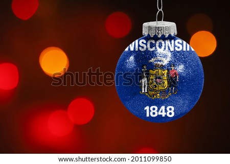 Colorful blurred background and applied the flag of State of Wisconsin on the New Year's toy. New Year 2022 Celebration