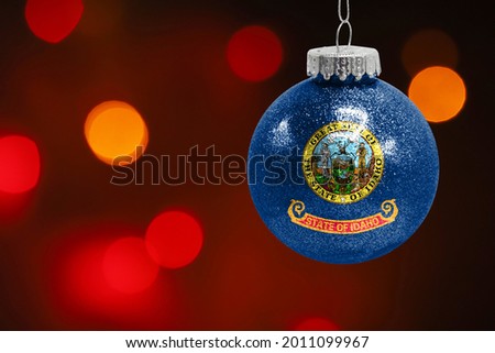 Colorful blurred background and applied the flag of State of Idaho on the New Year's toy. New Year 2022 Celebration