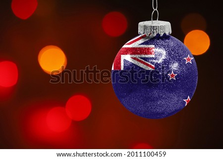 Colorful blurred background and applied the flag of New Zealand on the New Year's toy. New Year 2022 Celebration