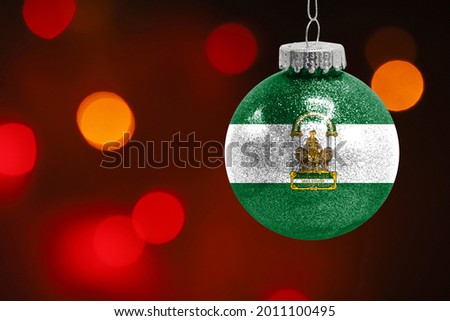 Colorful blurred background and applied the flag of Andalusia on the New Year's toy. New Year 2022 Celebration