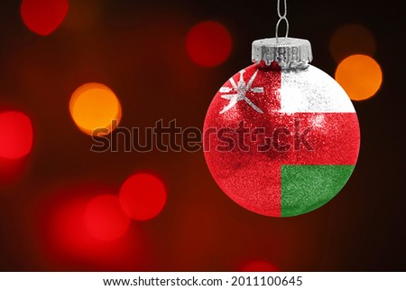 Colorful blurred background and applied the flag of Oman on the New Year's toy. New Year 2022 Celebration