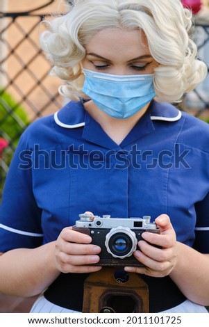 young blond woman in medicine mask with photo camera
