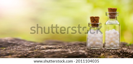 Homeopathic balls in bottles on the background of nature. Homeopathy alternative medicine concept. Royalty-Free Stock Photo #2011104035