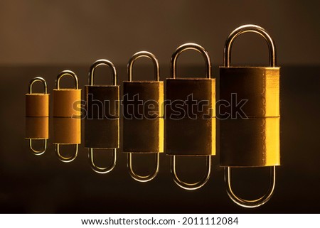 Group of locks, different sizes, placed in breeder manner on reflective material, on black background. 