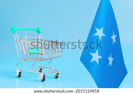 Empty metal shopping basket and the flag of the Federated States of Micronesia on a colored background the concept of a consumer basket