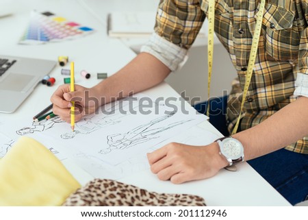 Unrecognizable fashion designer drawing sketches in his workshop