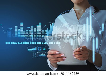 Hologram of financial bar graphs showing increase of world economy growth, globe icon. Business woman using tablet device to carry on a research